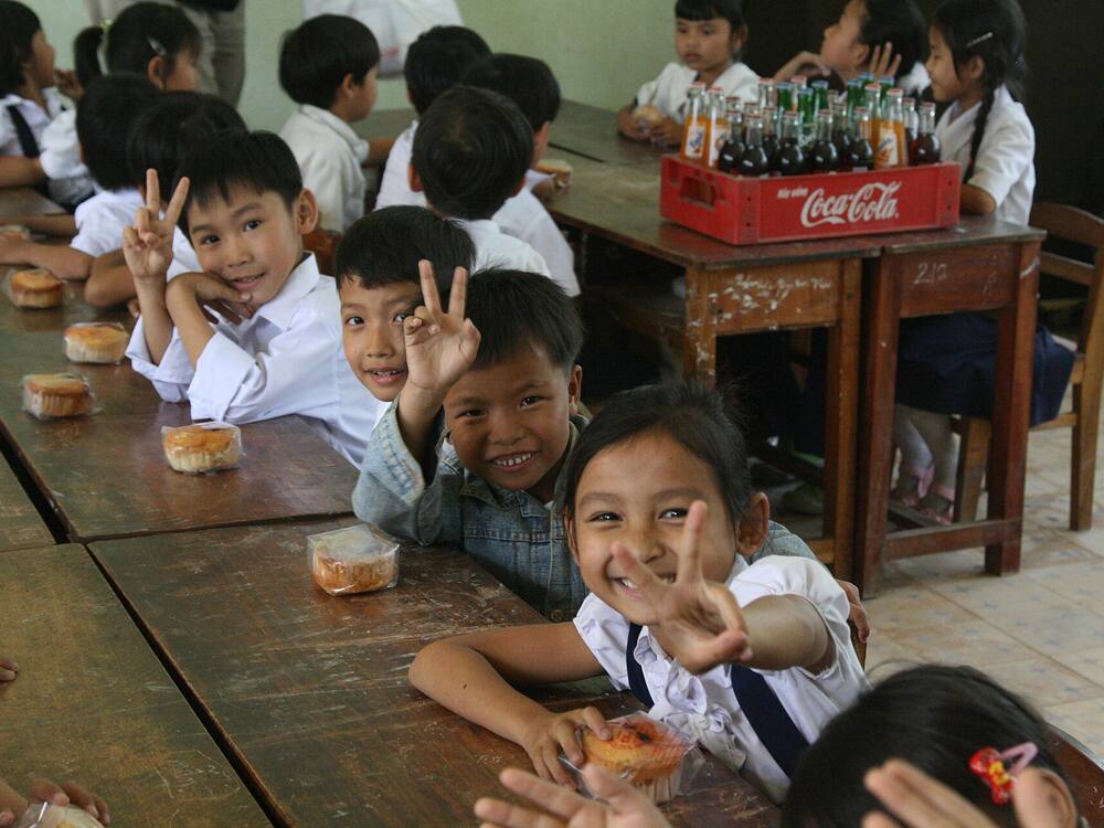 Các em học sinh tươi cười bên bữa ăn tại lớp