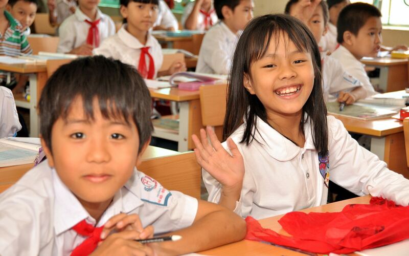 Hai em học sinh cười rạng rỡ bên bàn học